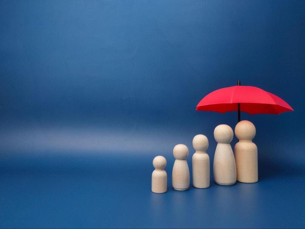 koncepcja zabezpieczenia przyszłości rodziny - parasole pod pionkami