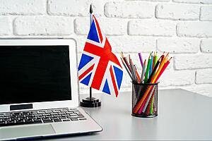 Otwarty laptop, a obok fllaga UK