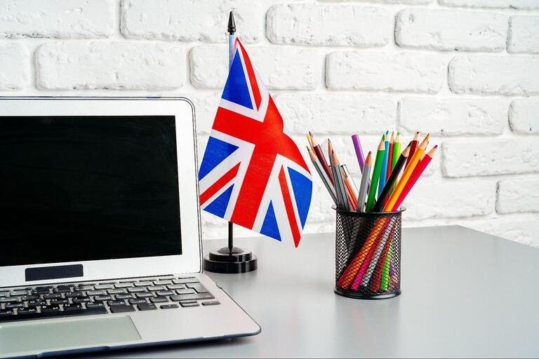 Otwarty laptop, a obok fllaga UK